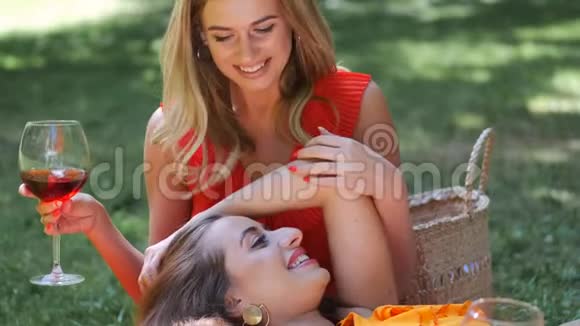 女孩躺在朋友的膝上在公园里喝酒视频的预览图