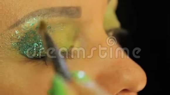 一个拿着刷子的女人眼睛上布满了绿色的阴影多汁的绿色火花视频的预览图
