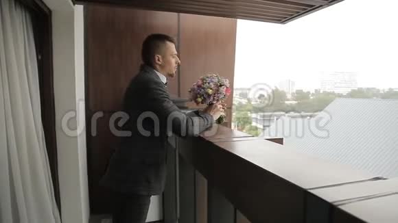 新郎站在阳台上手里拿着一束花视频的预览图