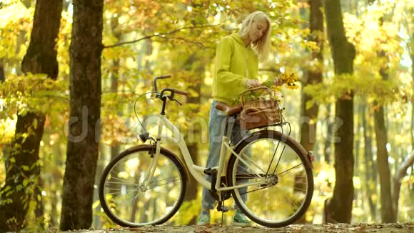 秋天的女人在秋天的公园里穿着绿色的套头衫好好享受无忧无虑的女人女孩手里拿着旧自行车把手视频的预览图