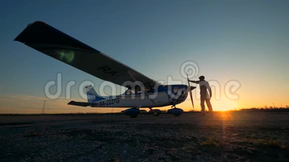 男性飞行员在日落背景下清洁飞机侧视视频的预览图