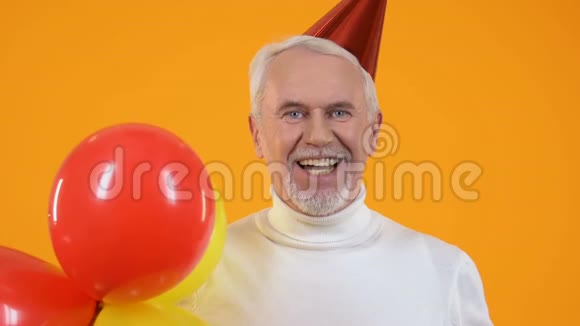 欢乐的高级男子派对帽子吹着手拿气球的噪音制造者庆祝视频的预览图