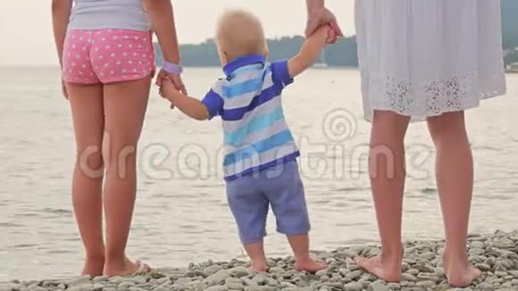 妈妈和姐姐手牵小男孩在沙滩自然户外信任家庭观念家人手牵手视频的预览图
