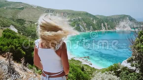 快乐和幸福的概念年轻的金发女人摇动她的头发头发在风中飞扬她享受着奇妙的海景视频的预览图
