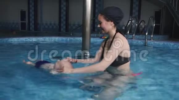 小男孩在游泳池里学游泳一位年轻的母亲教她的小儿子如何游泳视频的预览图