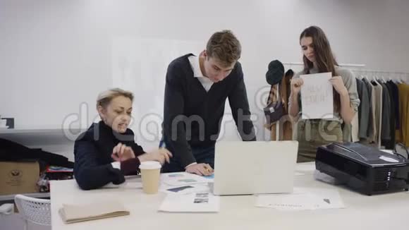 年轻的商人成年的女商人和年轻的雇员在一个服装室用笔记本电脑做这个项目视频的预览图