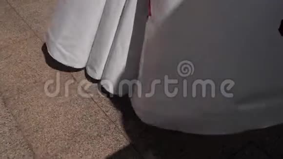 一个女人穿着一条镶着红花的白色裙子走上台阶用石头做的台阶和栏杆视频的预览图