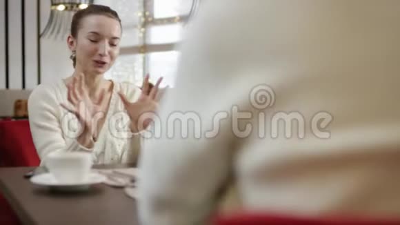 年轻女子在餐馆里和朋友聊天时大笑视频的预览图