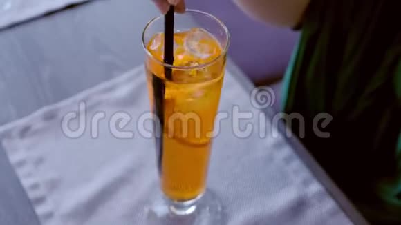 女人把酒精鸡尾酒和吸管混合在香槟笛子上用橙色喝双手特写视频的预览图
