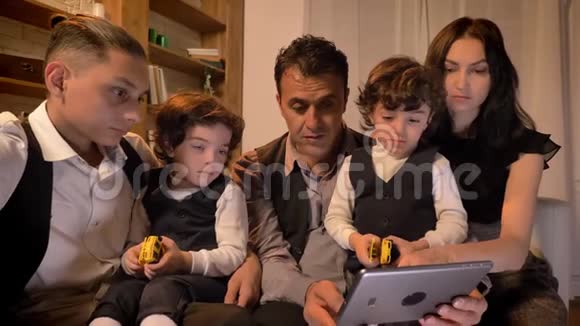 阿拉伯家庭坐在沙发上聚精会神地看着客厅里舒适的平板电脑的画像视频的预览图