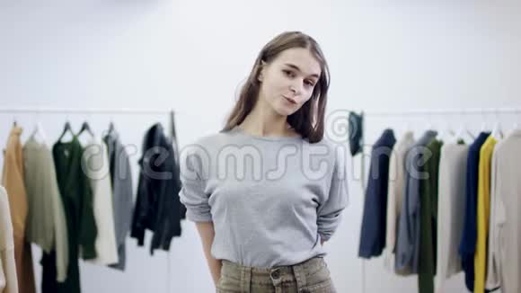 年轻漂亮的女人从某人身上拿出一件毛衣并在服装室里摆姿势视频的预览图