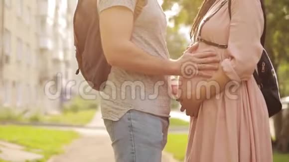 男人手摸着站在街上的孕妇的腹部视频的预览图