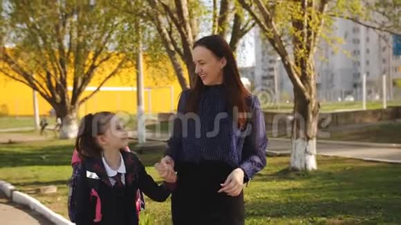 妈妈正带着小女孩穿着校服上学母女俩一起牵手上学视频的预览图