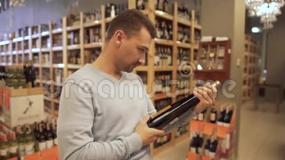 帅哥在一家酒店里学习酒瓶上的标签酒瓶站在木架上视频的预览图