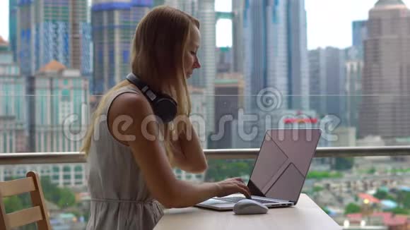 年轻女性自由职业者在她的笔记本电脑上工作在一个阳台上的手机上交谈背景是视频的预览图