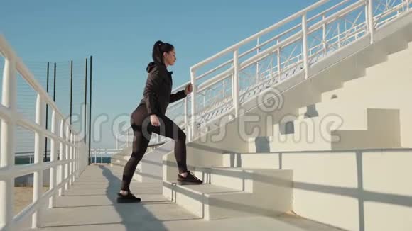 女性健身教练在锻炼慢动作前在室外跑步的侧视图视频的预览图
