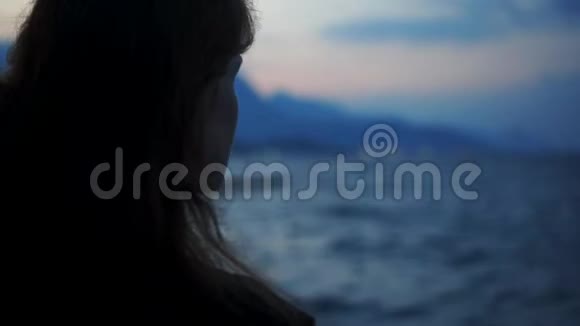 红发女人在海边看日落背景是山视频的预览图