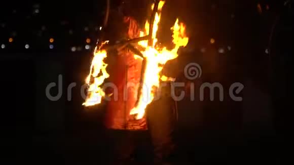 街上危险的火灾表演一个穿着服装的人拿着燃烧的椅子视频的预览图