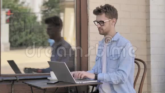 坐在户外的年轻人使用笔记本电脑视频的预览图