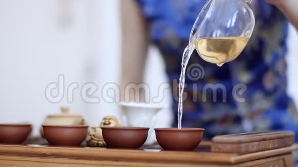 中国的茶道一个穿着蓝色衣服的女孩优雅地把茶倒入特殊的杯子里视频的预览图