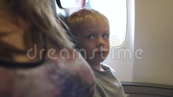 靠窗坐在飞机座位上的小男孩的肖像视频的预览图