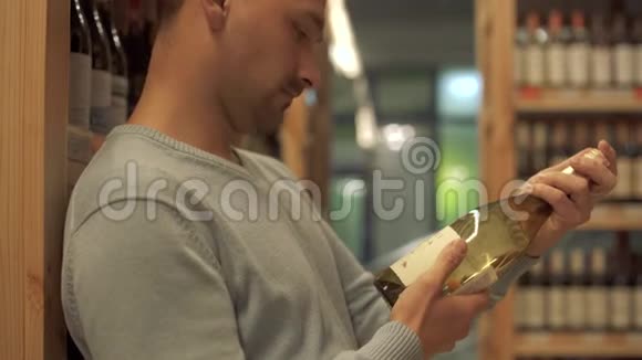 有魅力的家伙仔细检查了白酒商店一个白酒瓶标签上的成分酒瓶是视频的预览图
