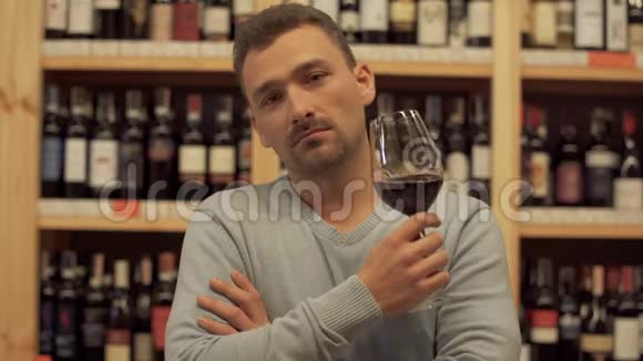 英俊男子喝红酒的肖像人摇动他的饮料举起酒杯喝一口酒视频的预览图