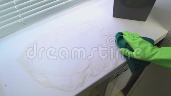 一只手戴绿色防护手套用蓝色潮湿的抹布清洗窗台使其不受灰尘和污垢的影响视频的预览图