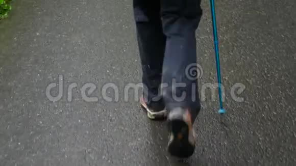 一个男人用追踪棒在沥青上行走只能看到腿视频的预览图