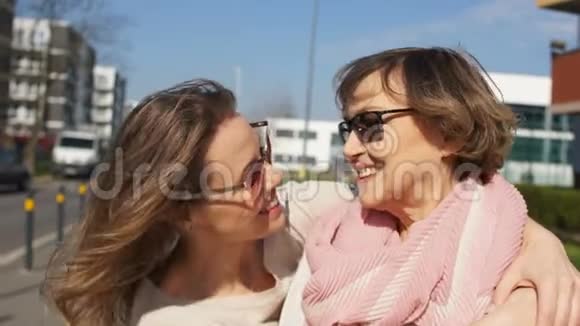城市街道上一对母女的亲密肖像晴天戴眼镜的女人笑着拥抱视频的预览图