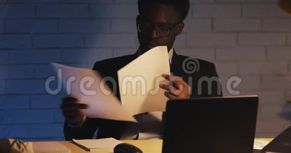 年轻的黑人厌倦了处理文件于是举起眼镜揉揉眼睛工作狂工作努力夜晚视频的预览图
