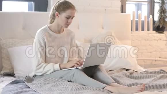 背疼的年轻女子在床上工作视频的预览图
