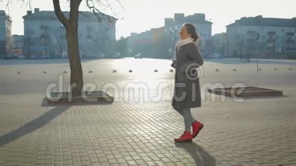年轻时尚的女孩穿着外套和眼镜走在城市的街道上视频的预览图