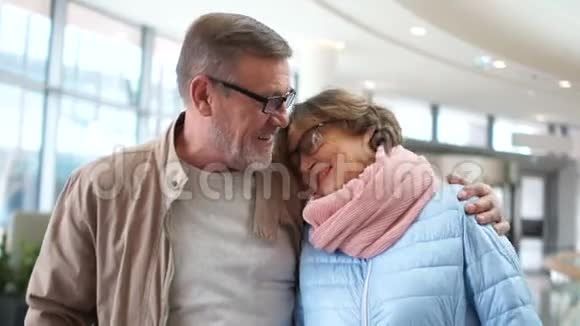 一对可爱的成熟夫妇在机场等着他们的航班笑着说话女人把男人头放在他身上视频的预览图