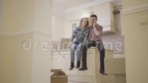 幸福的年轻夫妇坐在一间新公寓的厨房桌子上讨论房子的布局家庭搬迁到视频的预览图