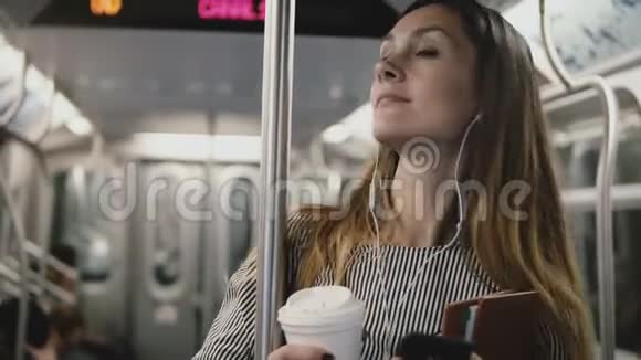 快乐成功的漂亮女商人在地铁列车上享受音乐耳机使用智能手机聊天应用微笑视频的预览图
