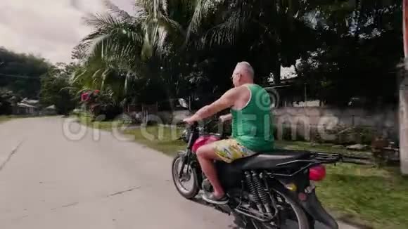暑假期间老人在农村驾驶摩托车戴太阳镜的老人骑摩托车上街视频的预览图