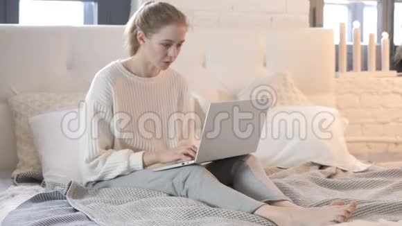 令人震惊的年轻女性想在床上玩手提电脑视频的预览图