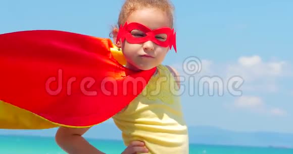 特写肖像美丽的小女孩穿着超级英雄服装穿着红色斗篷和英雄的面具土地视频的预览图
