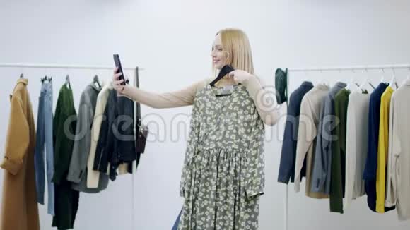 一位有魅力的成年女士正在试衣间用一件连衣裙拍几张照片视频的预览图