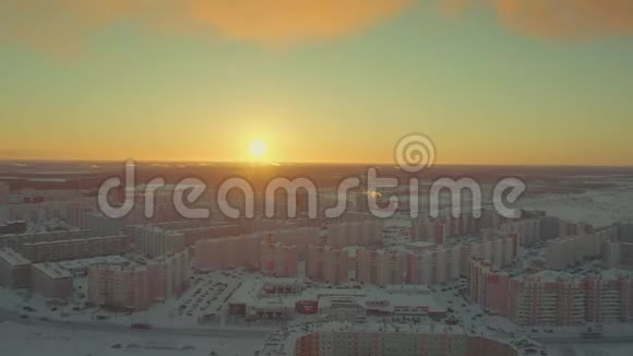 太阳在一个冬天的小镇的地平线上升起雪轻轻地落在建筑物上视频的预览图