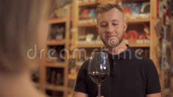 一家酒类商店的男性访客拿着提供的酒杯嗅着酒的香气焦点从女孩身上转移视频的预览图