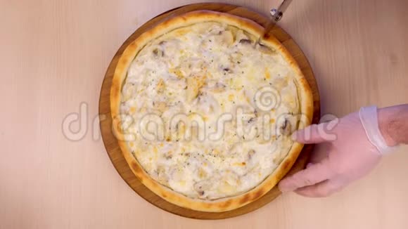 厨师在桌子上的木板上用蘑菇香瓜和奶酪切比萨饼特写俯视图视频的预览图