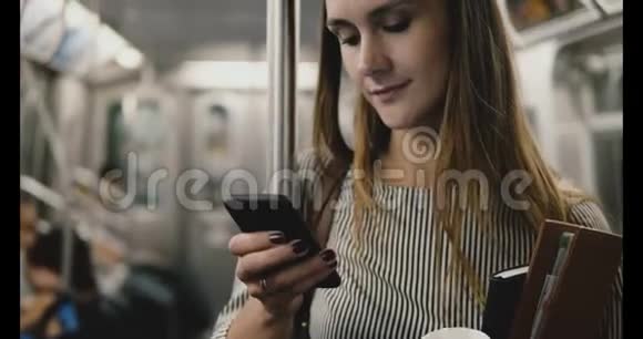 快乐轻松美丽的女首席执行官坐在地铁列车上看智能手机使用信使聊天应用微笑视频的预览图