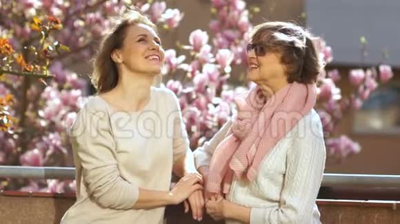成年母亲和女儿站在阳台上谈论一朵盛开的玉兰花国际妇女日视频的预览图