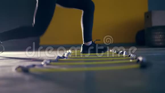 特写女腿穿黑色紧身裤和运动鞋女人和运动员一起做运动脚梯跳跃视频的预览图