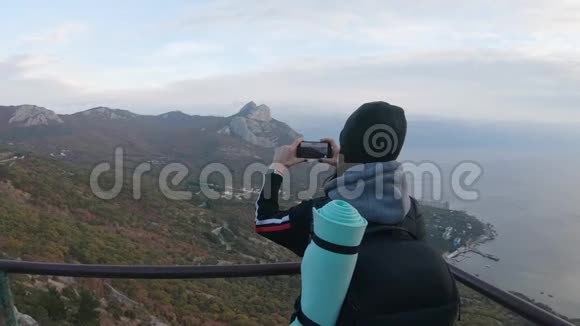 山顶上的女孩在手机上拍照的女游客年轻女性旅行者的背景视频的预览图