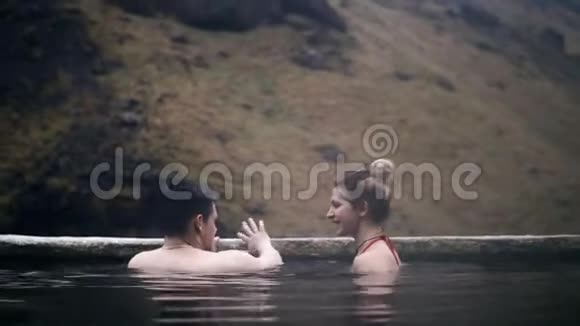 年轻夫妇在冰岛的温泉里放松游男女游山谷浪漫约会视频的预览图