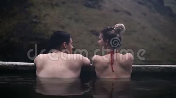 冰岛温泉中年轻夫妇的后景旅行的男人和女人在山区山谷放松视频的预览图