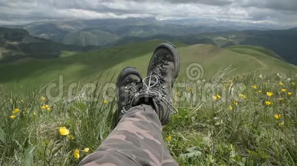在山顶上一个独立的男性旅行者的登山靴的特写镜头看风景视频的预览图
